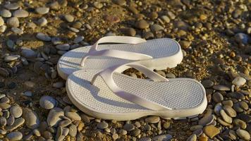 weiße Strandschuhe auf einem Hintergrund aus Sand und Kieselsteinen. foto