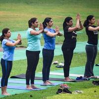 neu delhi, indien, 18. juni 2022 - gruppen-yoga-übungskurs für menschen unterschiedlichen alters im lodhi garden park. internationaler tag des yoga, große gruppe von erwachsenen, die draußen im park einen yogakurs besuchen foto