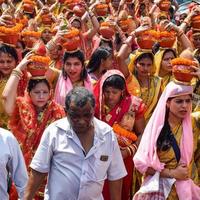 neu delhi, indien 03. april 2022 - frauen mit kalash auf dem kopf während des jagannath-tempels mangal kalash yatra, indische hindu-anhänger tragen irdene töpfe mit heiligem wasser mit einer kokosnuss darauf foto