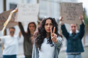 Geste mit zwei Fingern zeigen. Eine Gruppe feministischer Frauen protestiert im Freien für ihre Rechte foto