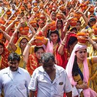 neu delhi, indien 03. april 2022 - frauen mit kalash auf dem kopf während des jagannath-tempels mangal kalash yatra, indische hindu-anhänger tragen irdene töpfe mit heiligem wasser mit einer kokosnuss darauf foto