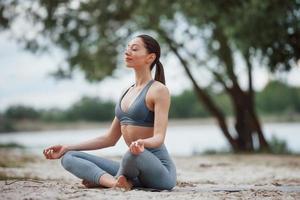 Meditation mit Naturgeräuschen. brünette mit schöner körperform in sportlicher kleidung haben einen fitnesstag am strand foto