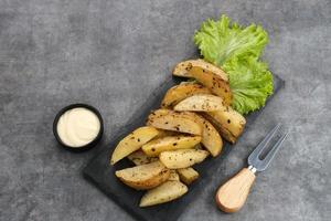 Geröstete Kartoffelecken mit Rosmarin und Kräutern, serviert mit Mayonnaise-Sauce foto