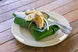 eingewickeltes thailändisches Essensset mit Bananenblatt, servierfertig. Im Inneren des Bananenblatts befindet sich Padthai, die traditionelle thailändische gebratene Nudel mit Garnelen. foto