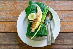 eingewickeltes thailändisches Essensset mit Bananenblatt, servierfertig. Im Inneren des Bananenblatts befindet sich Padthai, die traditionelle thailändische gebratene Nudel mit Garnelen. foto