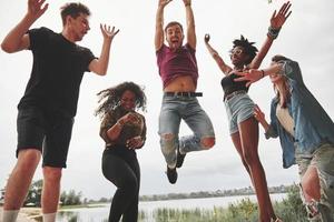 beim Springen feiern. gruppe von menschen picknickt am strand. Freunde haben Spaß am Wochenende foto