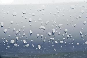 Wassertropfen auf der weißen Oberfläche des Autos foto