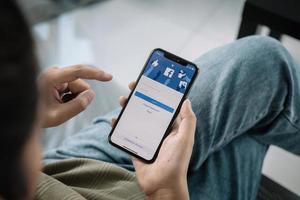 Facebook-Social-Media-App-Logo auf der Registrierungsseite für die Anmeldung auf dem Bildschirm der mobilen App auf dem iPhone x 10 in der Hand einer Person, die am E-Commerce-Einkaufsgeschäft arbeitet. foto