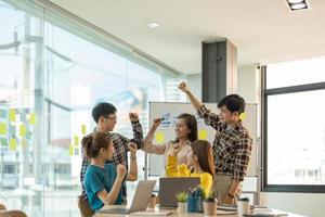 junges asiatisches geschäftsteam erfolgsleistung arm erhoben, teamwork zusammenarbeit, teambuilding oder erfolgsgeschäftsprojektkonzept foto