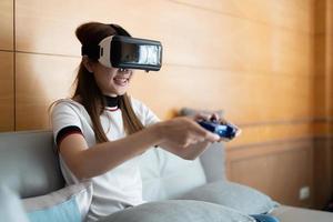nahaufnahme glückliche emotion asiatische frau, die videospiele mit controller auf abstraktem hintergrund spielt, der mit einer virtuellen brille getönt ist foto