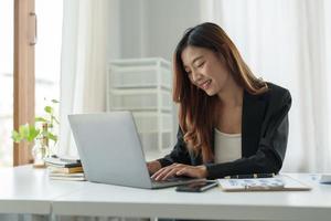 junge schöne asiatische frau, die auf laptop-computer für online-webinar tippt und virtuelle internet-online-klasse vom schullehrer per remote-meeting lernt foto