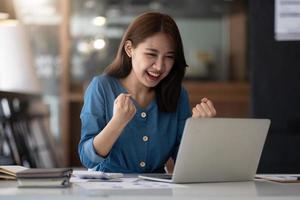 Aufgeregte asiatische Frau, die sich euphorisch fühlt und das Ergebnis des Online-Erfolgs feiert, junge Frau freut sich über gute E-Mail-Nachrichten, motiviert durch ein großartiges Angebot oder eine neue Gelegenheit, bestandene Prüfung, hat einen Job bekommen foto