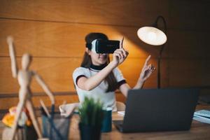 junge asiatische frau in vr-brille, die zu hause virtuell für finanzen arbeitet foto