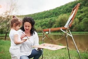 es ist nicht so schwer. Enkelin das Malen beibringen. in der Naturparklandschaft foto