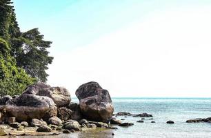 große Felsbrocken, die am Rande eines wunderschönen Strandes mit blauem Himmel liegen foto