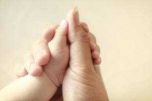 Baby hält den Finger seiner Mutter, selektiver Fokus