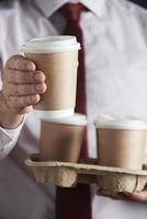 Geschäftsmann hält Tablett mit Kaffee zum Mitnehmen foto