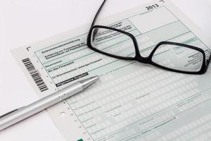 Form der Einkommensteuererklärung mit Kugelschreiber und Brille