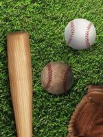 Baseball, Handschuh, Ball und Schläger auf dem Feld foto