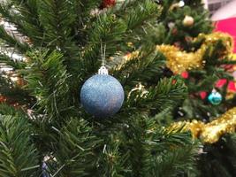 dekorierte weihnachtsgrüne baumdekorationen haben eine blaue kugel, goldene blätter auf einem verschwommenen hintergrund foto