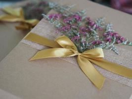 Geschenkbox aus braunem Papier, die mit einem goldenen Band gebunden und mit getrockneten Blumen, Festgeschenken für Weihnachten und ein frohes neues Jahr geschmückt ist foto