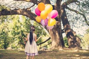 kleines Mädchen mit Luftballons in einem Feld foto