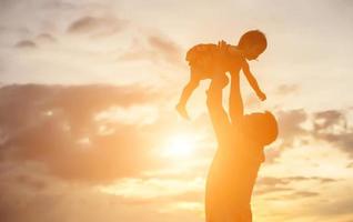 Vater brachte das Baby dazu, bei Sonnenuntergang laufen zu lernen. foto