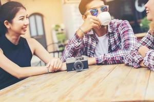 gruppe junger hipster, die in einem café sitzen, junge fröhliche freunde, die spaß haben, während sie sich zeit nehmen, urlaubsfreiheit genießen. foto