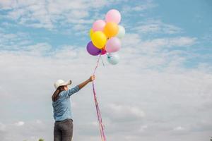 schönes Mädchen, das mit Luftballons am Strand springt foto