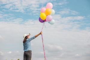 schönes Mädchen, das mit Luftballons am Strand springt foto