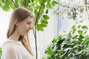 Seitenporträt eines Teenager-Mädchens in einem modernen Haus mit vielen grünen Pflanzen auf einem Hintergrund. generation z-konzept foto