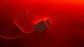 Weißes Spannungsladegerät mit USB-Kabel für Telefon- und Geräteladung auf farbigem und leuchtendem Hintergrund foto