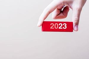 geschäftsmannhand, die 2023 holzblock hält. auflösung, strategie, lösung, ziel, risikogeschäft und neujahrsneustartkonzepte foto