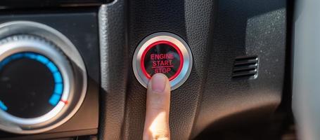 Drücken Sie mit dem Finger auf einen Zündknopf oder starten Sie den Motor in einem modernen Elektroauto. Keyless, Change, Strategie, Vision, Innovation und Zukunftskonzept foto