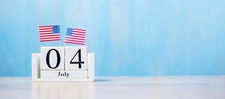 holzkalender vom 4. juli mit miniaturflagge der vereinigten staaten von amerika auf holzhintergrund. unabhängigkeitstag und nationales feiertagskonzept foto