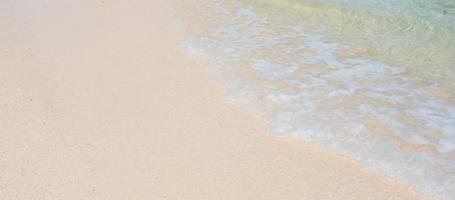 weiche welle aus blauem meerwasser und weißem sand am schönen strand. Hintergrund, Tapete und abstraktes Konzept foto