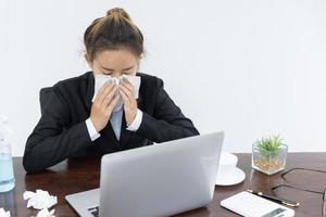weibliche Angestellte, die eine medizinische Maske tragen, während sie alleine arbeiten, Krankheit während der Arbeit. foto