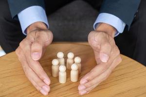 Geschäftsmann Hand Abdeckung Mann aus Holz von der Masse der Mitarbeiter. Menschen, Wirtschaft, Personalmanagement, Lebensversicherung, Teamarbeit und Führungskonzepte foto