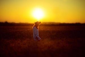Frau in einem Weizenfeld bei Sonnenuntergang