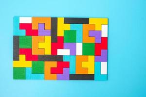 Bunte Holzpuzzleteile auf blauem Hintergrund, geometrischer Formblock. konzepte des logischen denkens, rätsel, lösungen, rational, strategie, weltlogiktag und bildung foto