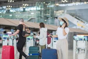 asiatische touristin, die eine gesichtsmaske trägt und ein mobiles smartphone am flughafen verwendet, schützt vor einer coronavirus-infektion. Reisezeit nach dem Impf-Booster-Dosierungskonzept foto