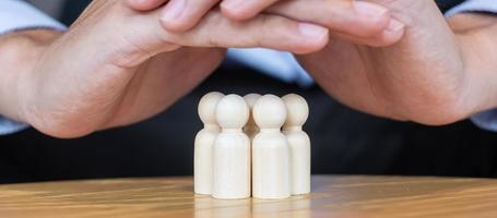 Geschäftsmann Hand Abdeckung Mann aus Holz von der Masse der Mitarbeiter. Menschen, Wirtschaft, Personalmanagement, Lebensversicherung, Teamarbeit und Führungskonzepte foto