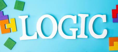 Logiktext mit bunten Holzpuzzleteilen, geometrischer Formblock auf blauem Hintergrund. konzepte des logischen denkens, rätsel, lösungen, rational, strategie, weltlogiktag und bildung foto