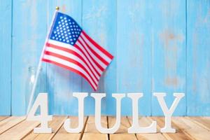 4. juli text und flagge der vereinigten staaten von amerika auf holztischhintergrund. usa feiertag der unabhängigkeit und feierkonzepte foto
