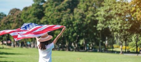 Frau, die mit der Flagge der Vereinigten Staaten von Amerika im Park im Freien reist. usa feiertag von veteranen, denkmal, unabhängigkeit und arbeitstagkonzept foto
