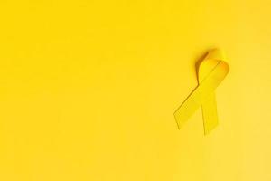 gelbes band auf gelbem hintergrund zur unterstützung von lebenden und kranken menschen. juli sarkom krebs, tag der selbstmordprävention, konzept des monats zur bewusstseinsbildung für kindeskrebs foto