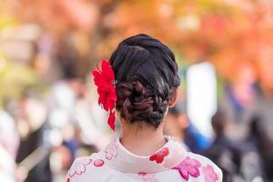 Junge Touristin im Kimono mit bunten Blättern im Kiyomizu-Dera-Tempel, Kyoto, Japan. asiatisches mädchen mit frisur in traditioneller japanischer kleidung in der herbstlaubsaison foto