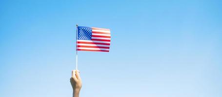Hand, die die Flagge der Vereinigten Staaten von Amerika auf blauem Himmelshintergrund hält. usa feiertag von veteranen, denkmal, unabhängigkeit und arbeitstagkonzept foto