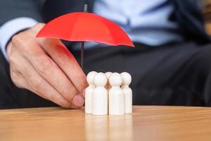 geschäftsmannhand, die regenschirm hält und abdeckungsmann hölzern von der menge der mitarbeiter. Menschen, Unternehmen, Personalmanagement, Lebensversicherung, Teamarbeit und Führungskonzepte foto