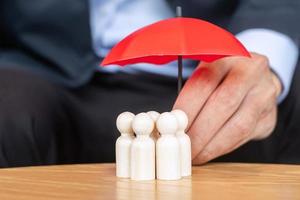 geschäftsmannhand, die regenschirm hält und abdeckungsmann hölzern von der menge der mitarbeiter. Menschen, Unternehmen, Personalmanagement, Lebensversicherung, Teamarbeit und Führungskonzepte foto